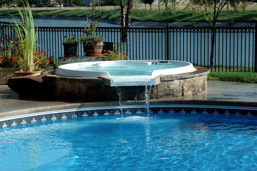 Hot tub with a waterfall spillover into inground pool
